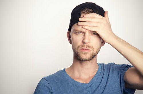 man in blue crew neck shirt covering his face